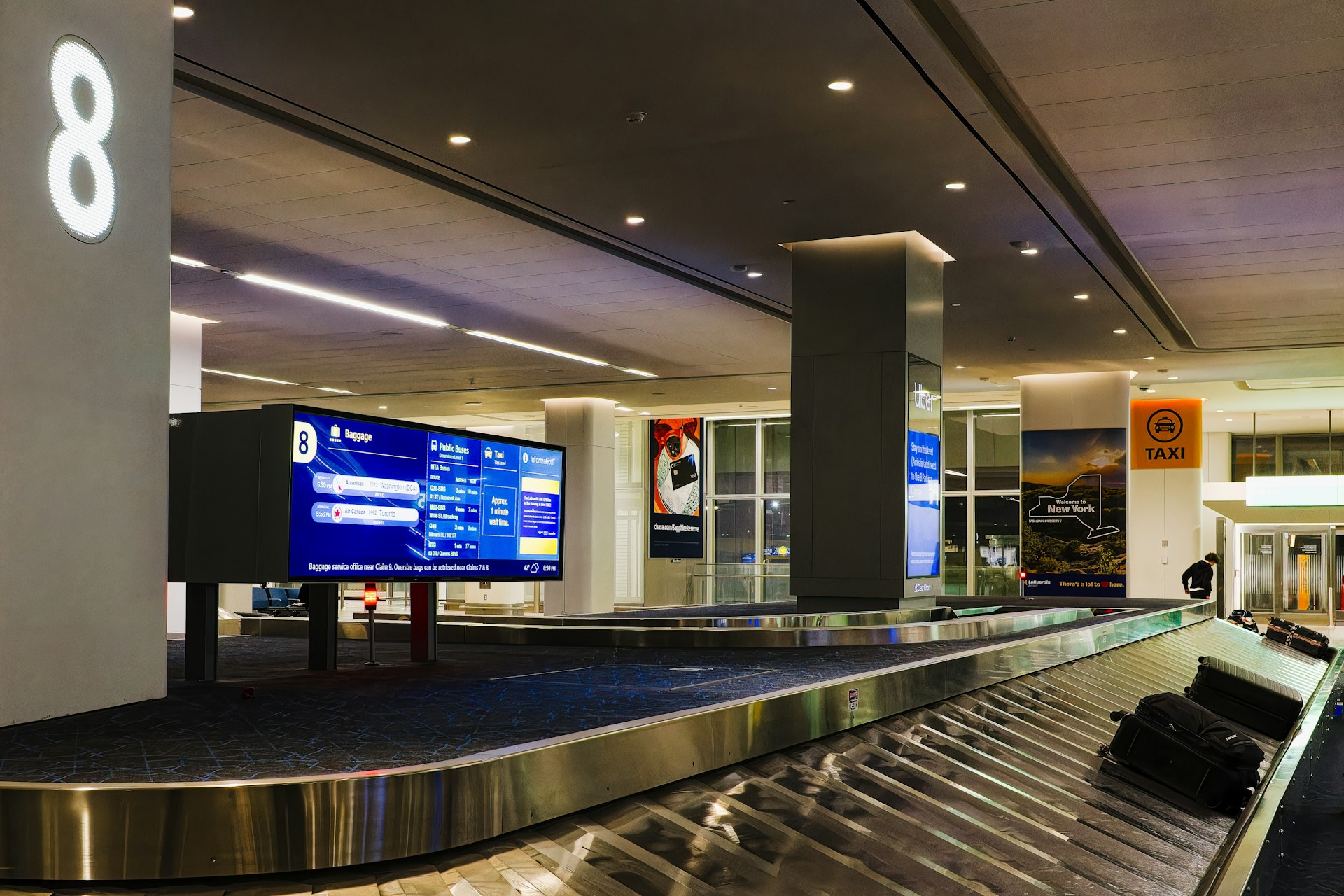Airport baggage claim carousel with overhead flight information screen