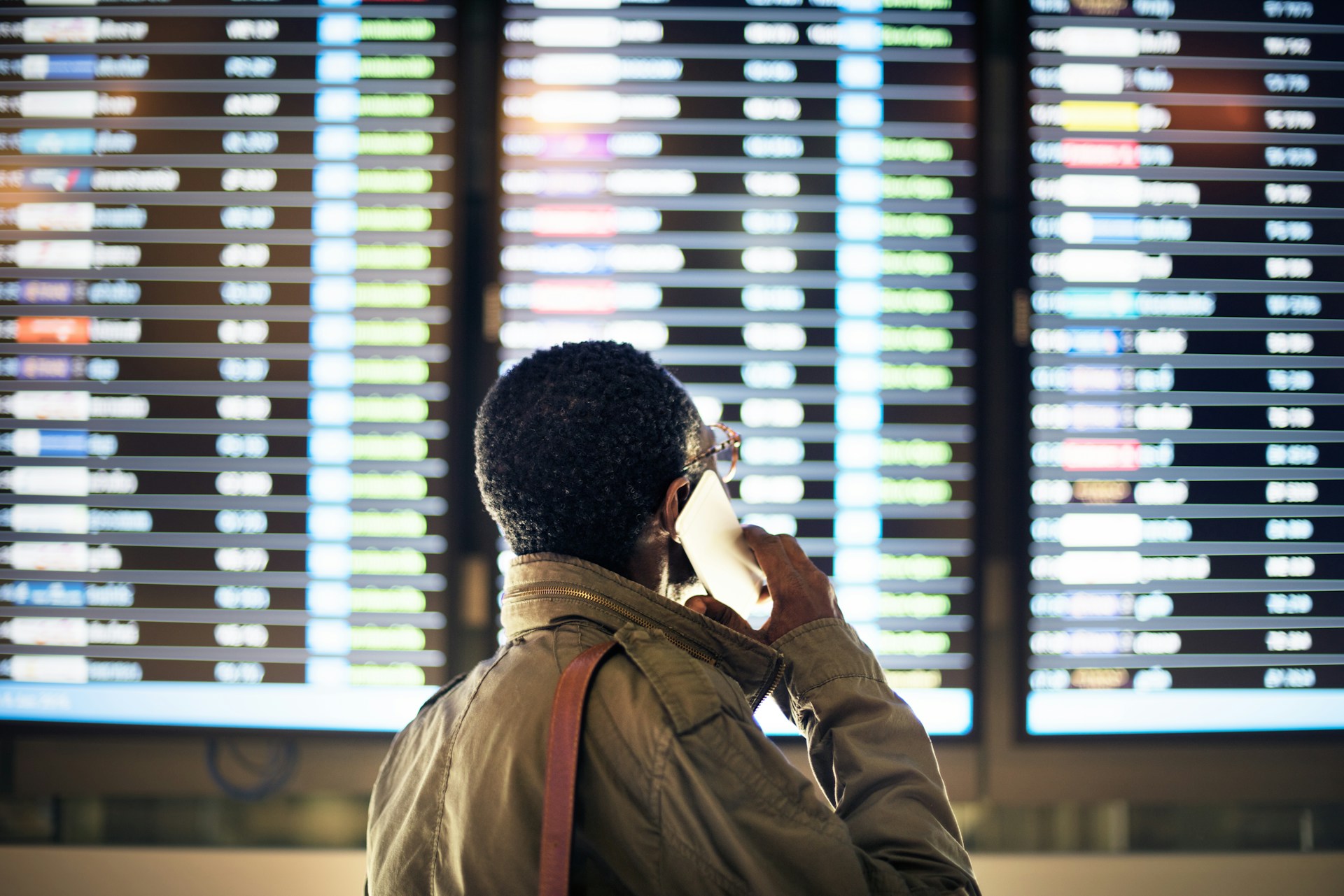 Airport departure board displaying updated flight times, including a delayed status