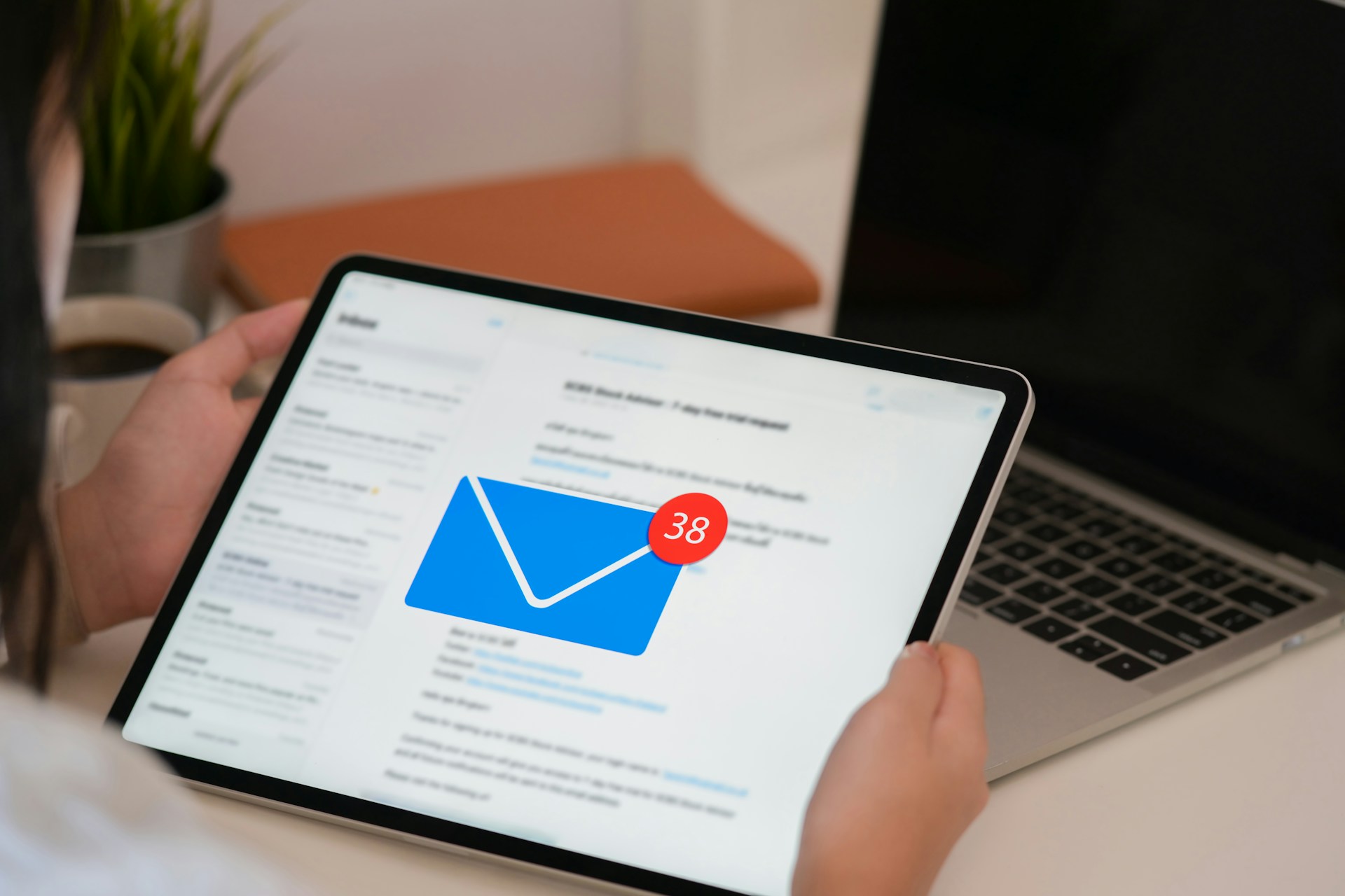 Close up of hands holding a tablet displaying an email inbox