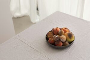 Bowl of fruit on a table showing signs of ripening and early spoilage