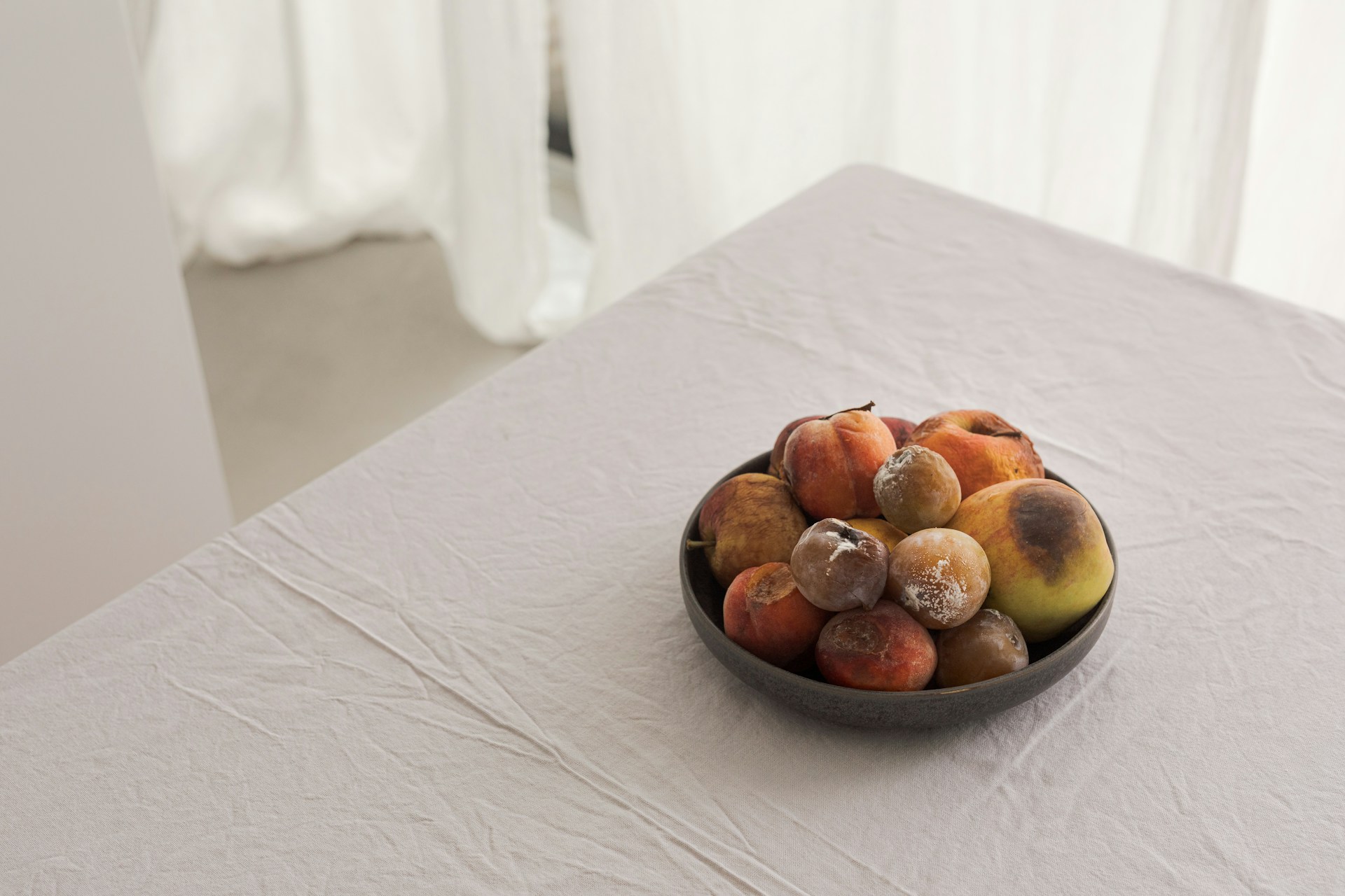 Bowl of fruit on a table showing signs of ripening and early spoilage