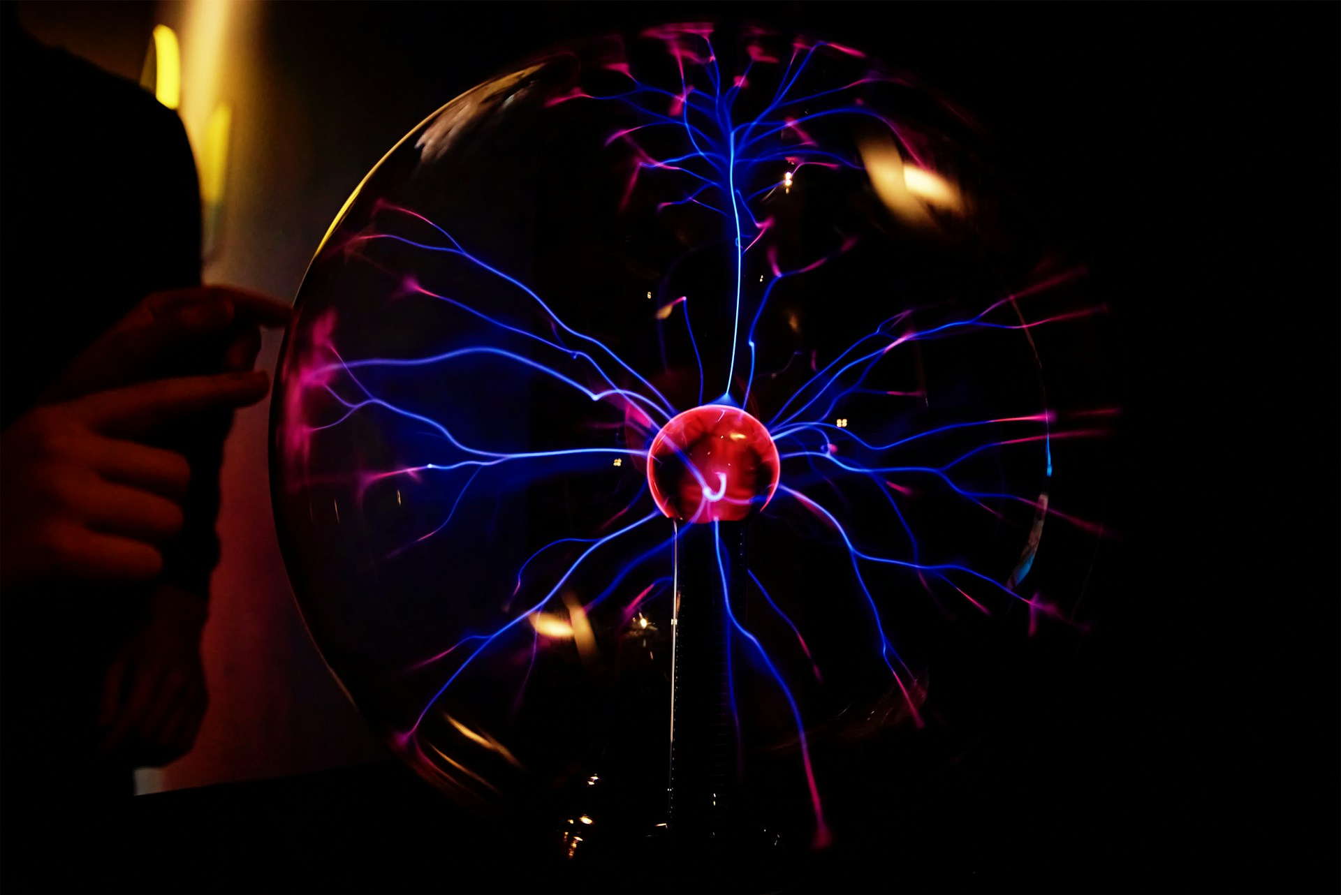 Plasma ball with visible electrical arcs inside a glass sphere against a dark background