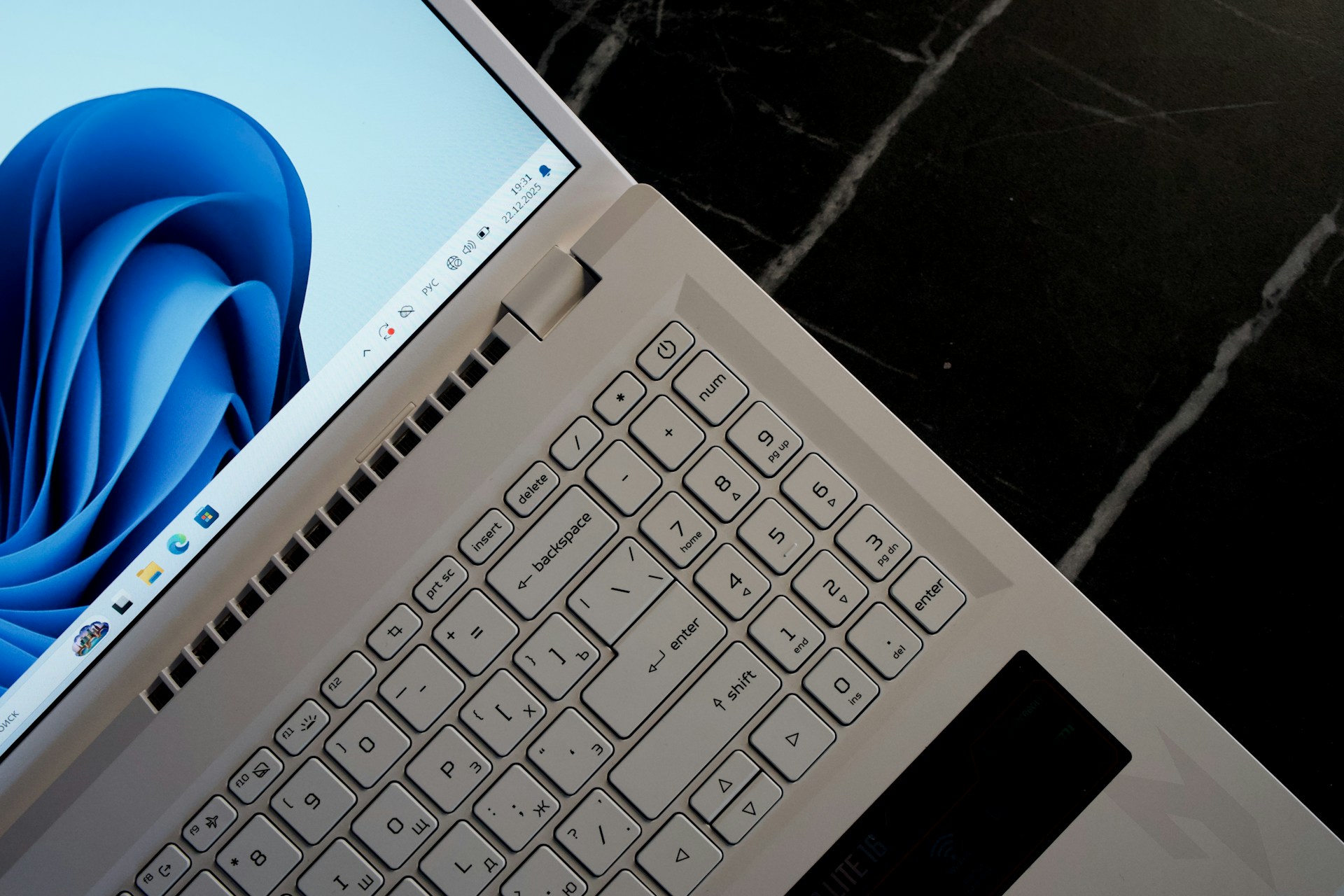 Open white laptop displaying a blue abstract wallpaper on the screen