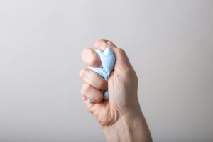 Person squeezing an object tightly in one hand, illustrating physical tension