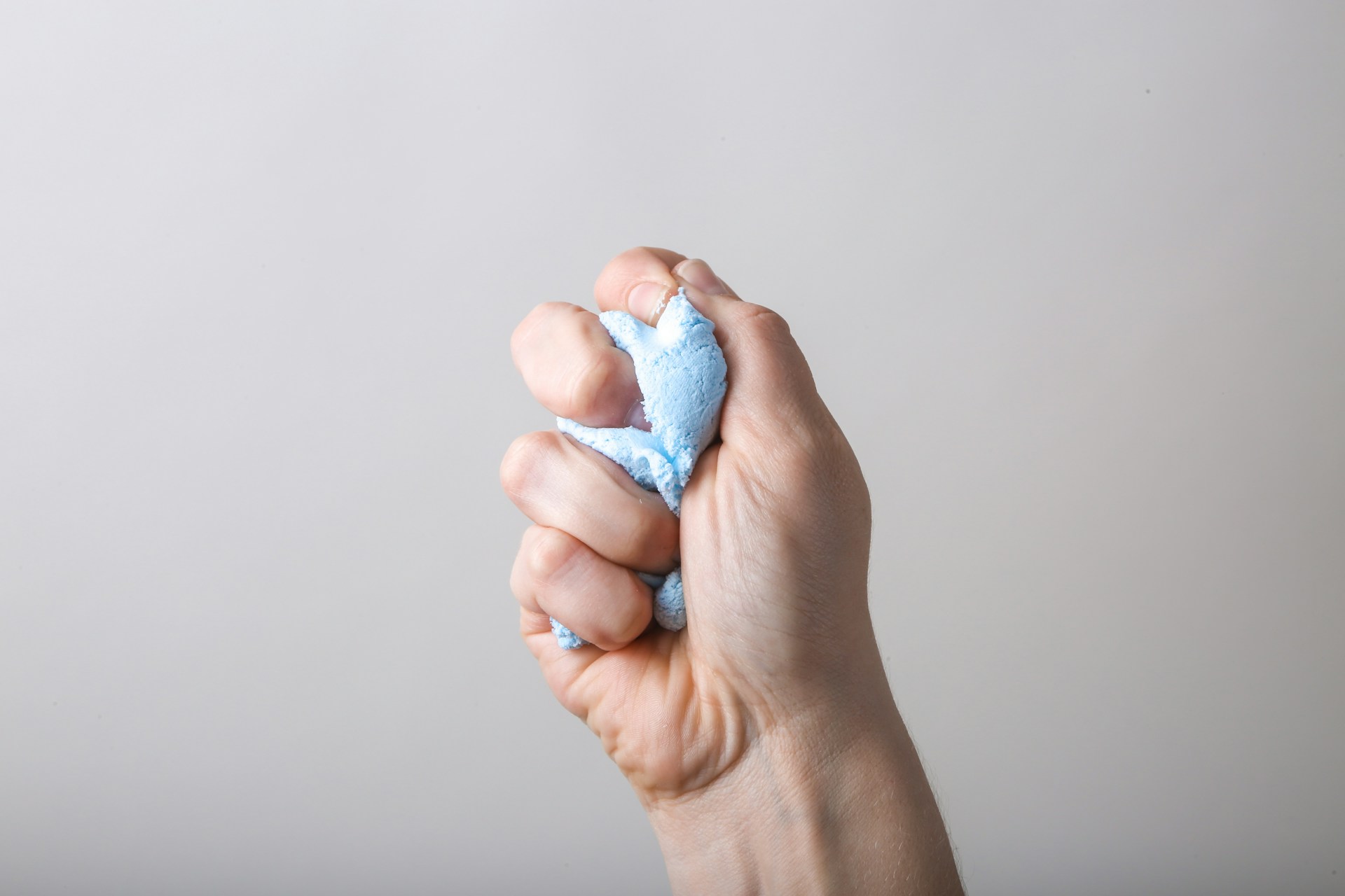Person squeezing an object tightly in one hand, illustrating physical tension