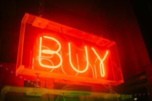 Neon sign displaying the word “Buy” against a dark background
