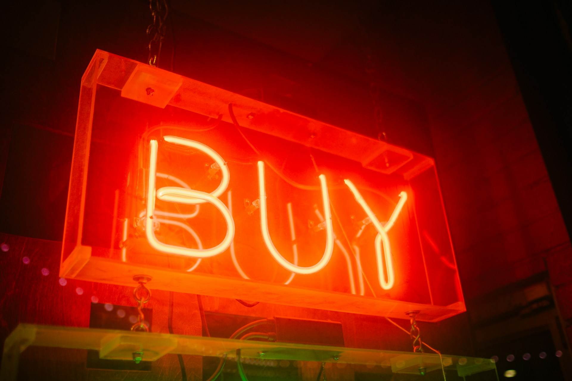Neon sign displaying the word “Buy” against a dark background