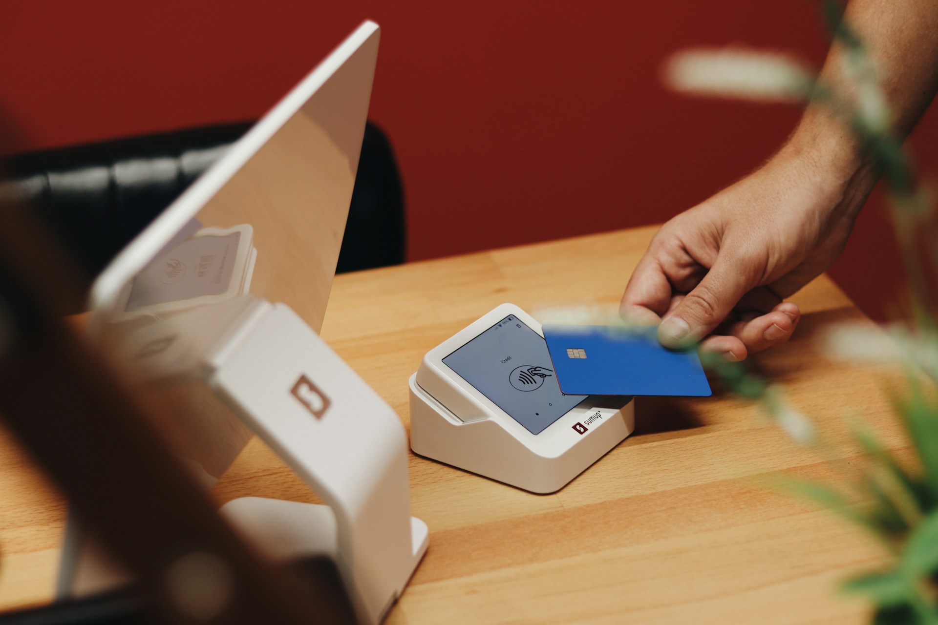Person tapping a credit card on a payment terminal for a contactless transaction