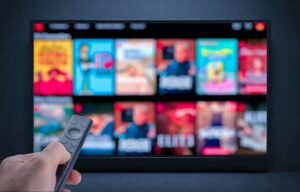Television screen displaying multiple streaming service thumbnails with a remote control in view