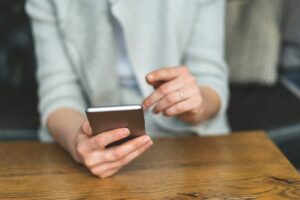 Person holding a smartphone while viewing payment or banking activity indoors
