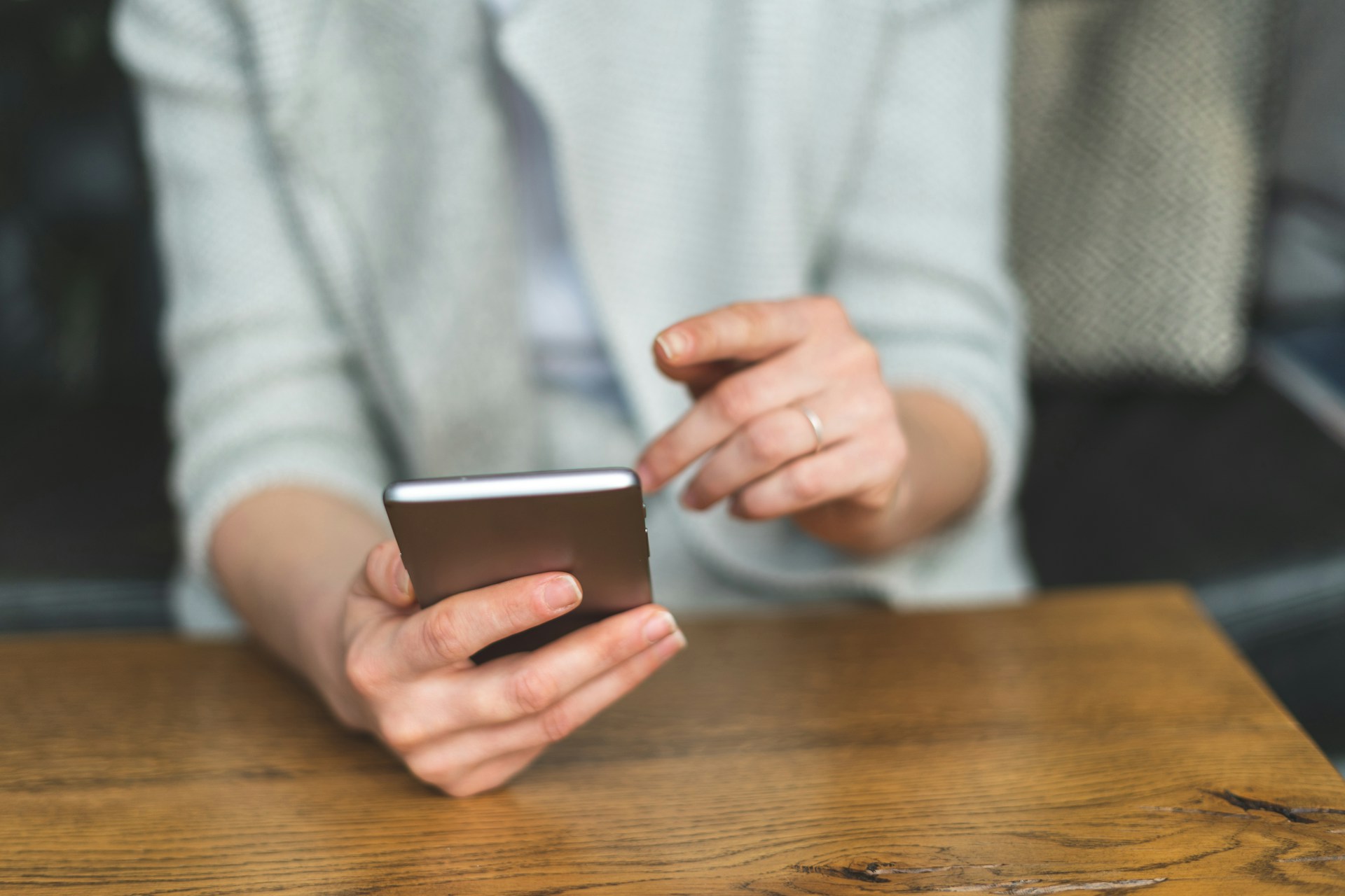 Person holding a smartphone while viewing payment or banking activity indoors