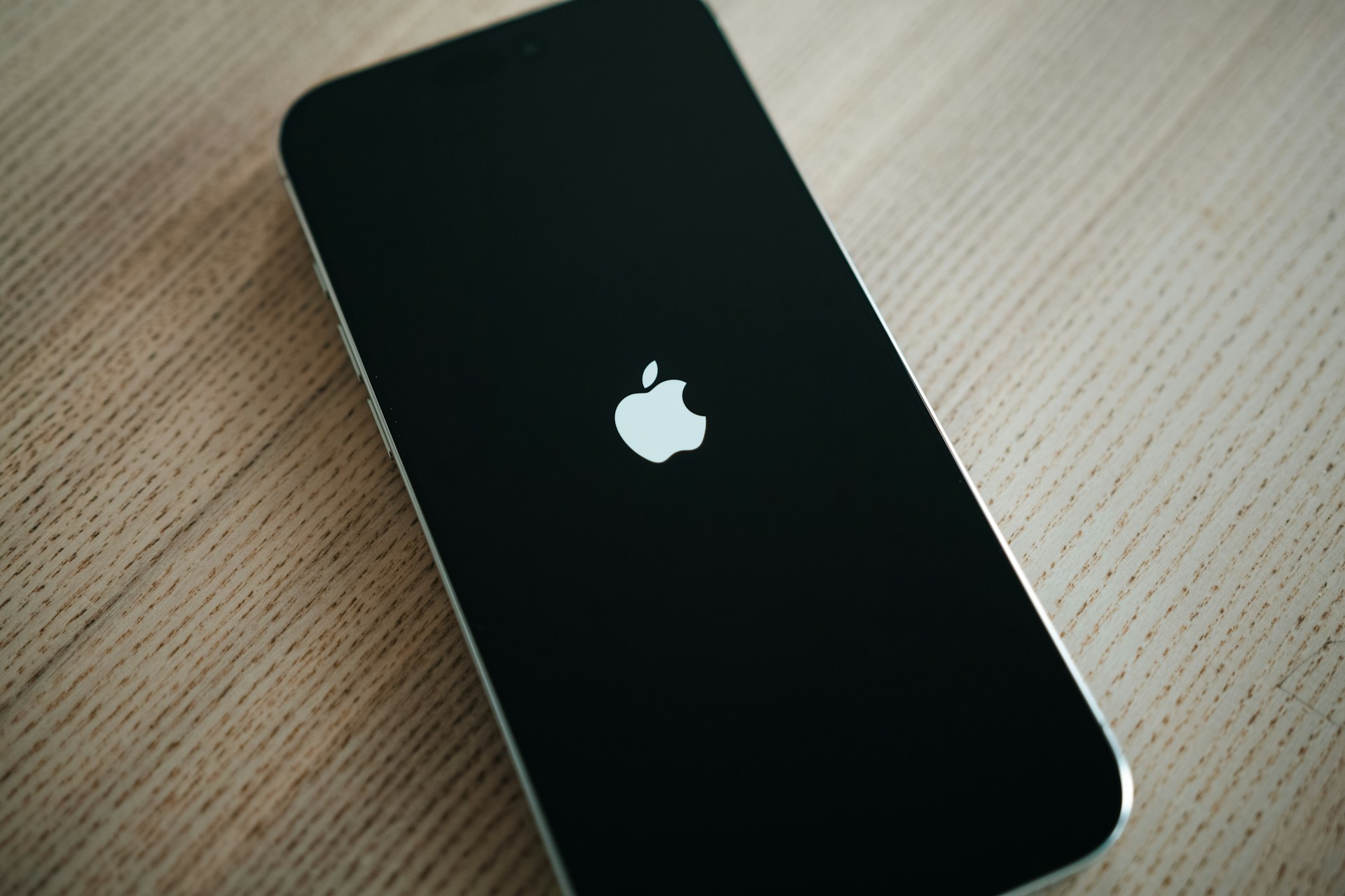 Black iPhone resting on a wooden table with the screen turned on