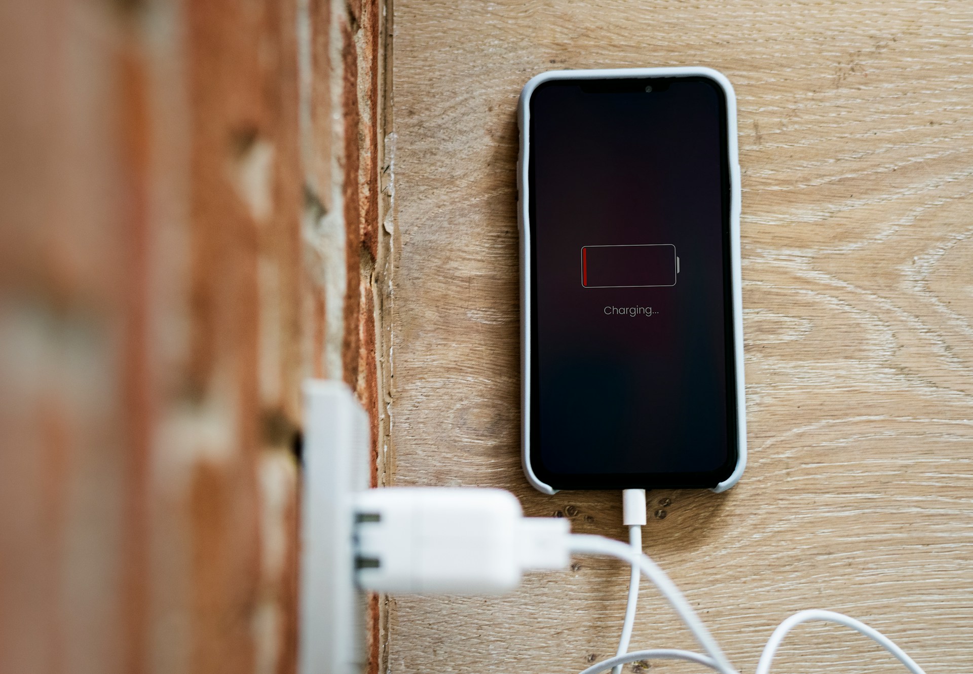 Smartphone screen showing a low battery icon while connected to a charging cable.