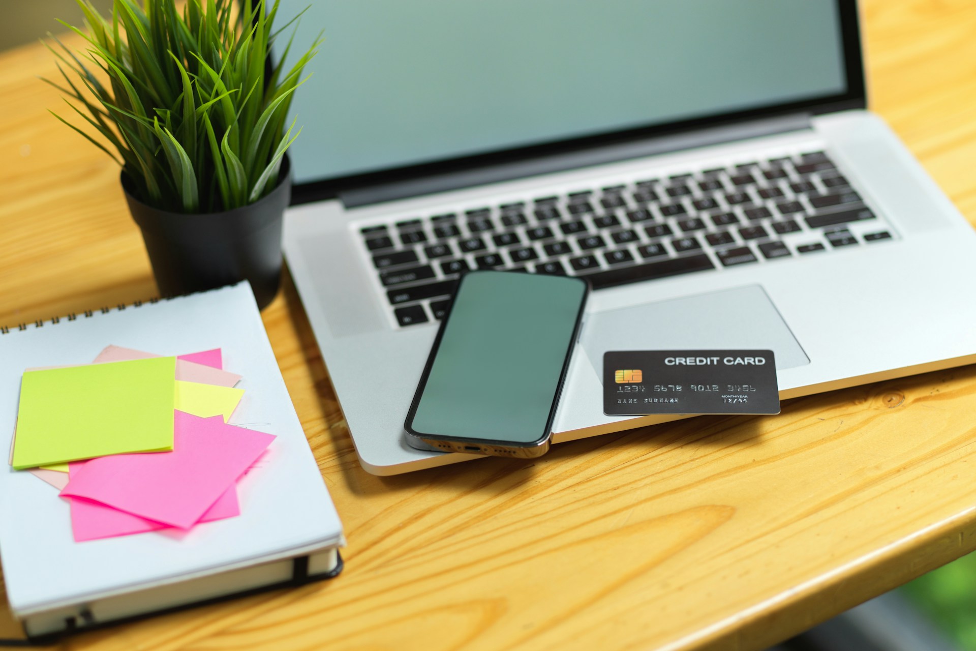 Mobile phone, laptop, and credit card on a desk representing automatic online payments and recurring billing.