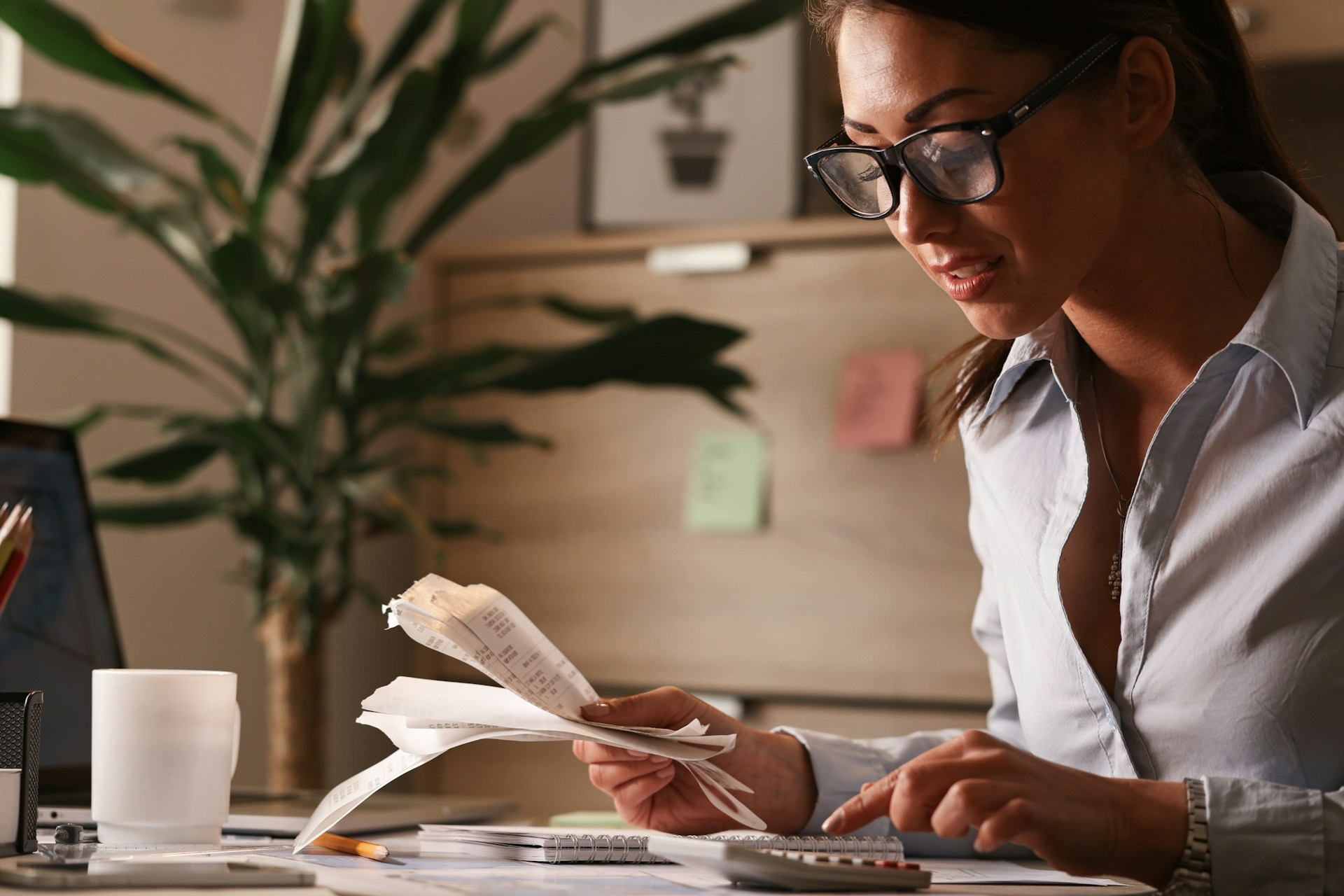Person using a calculator while reviewing bank statements and financial documents.