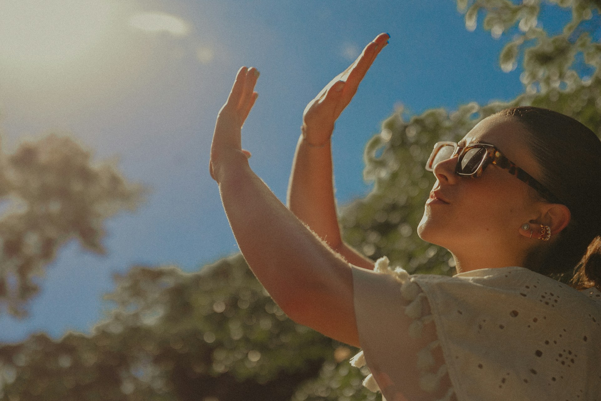 Person outdoors shielding their eyes from bright sunlight.