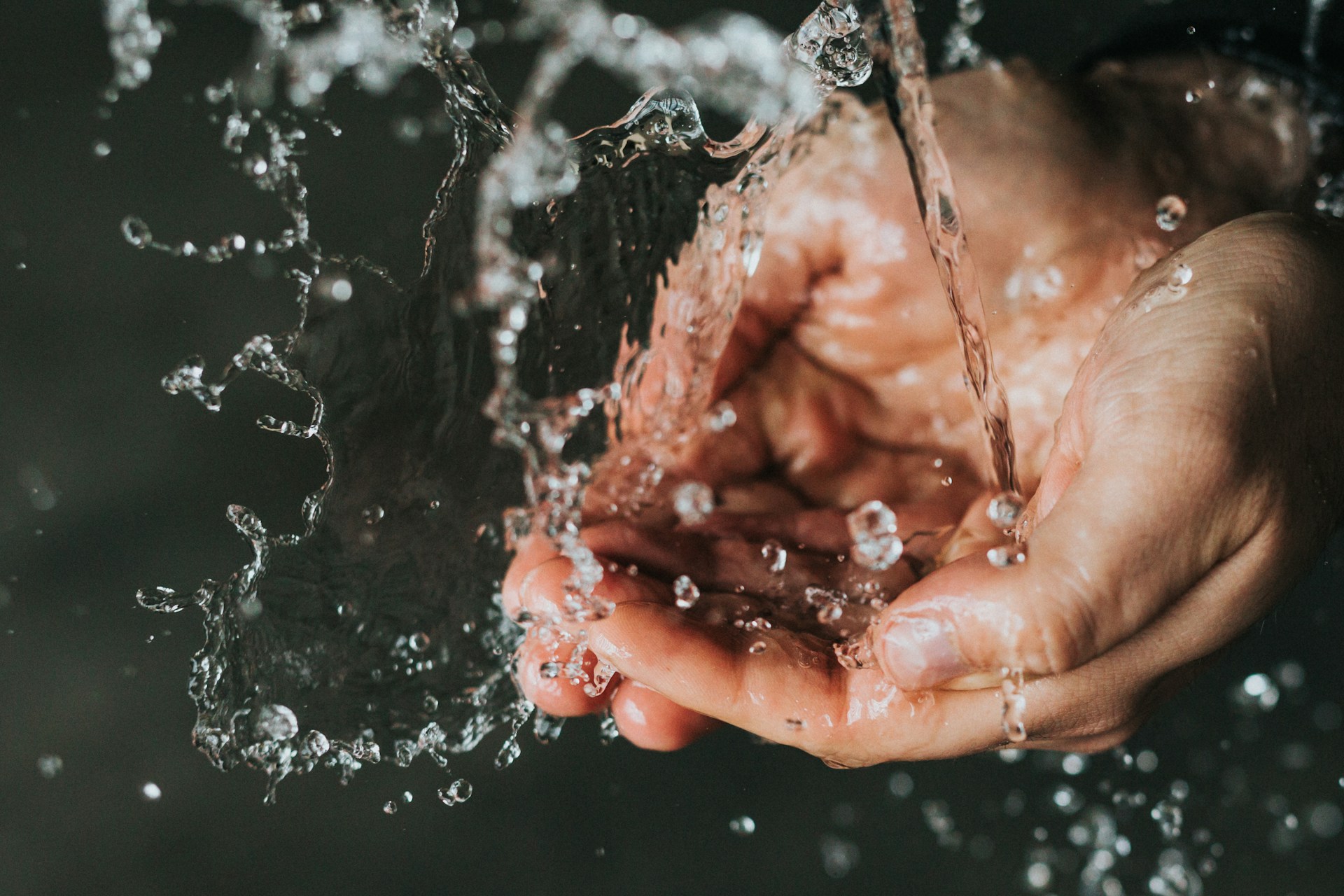 Person holding their hands under running water, illustrating how prolonged water exposure causes fingers to wrinkle.