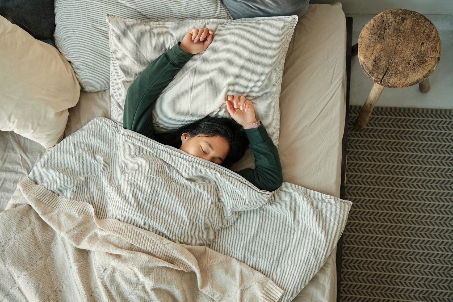 Woman sleeping in bed under a blanket at night, representing sleep and nighttime teeth grinding.