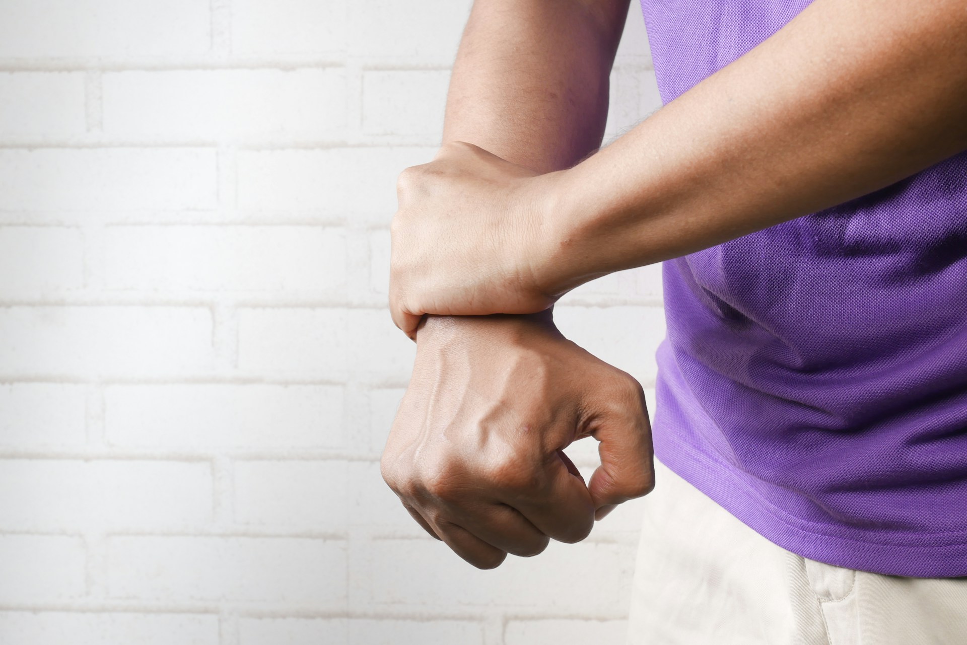 Person gently holding and stretching a hand experiencing a muscle cramp.