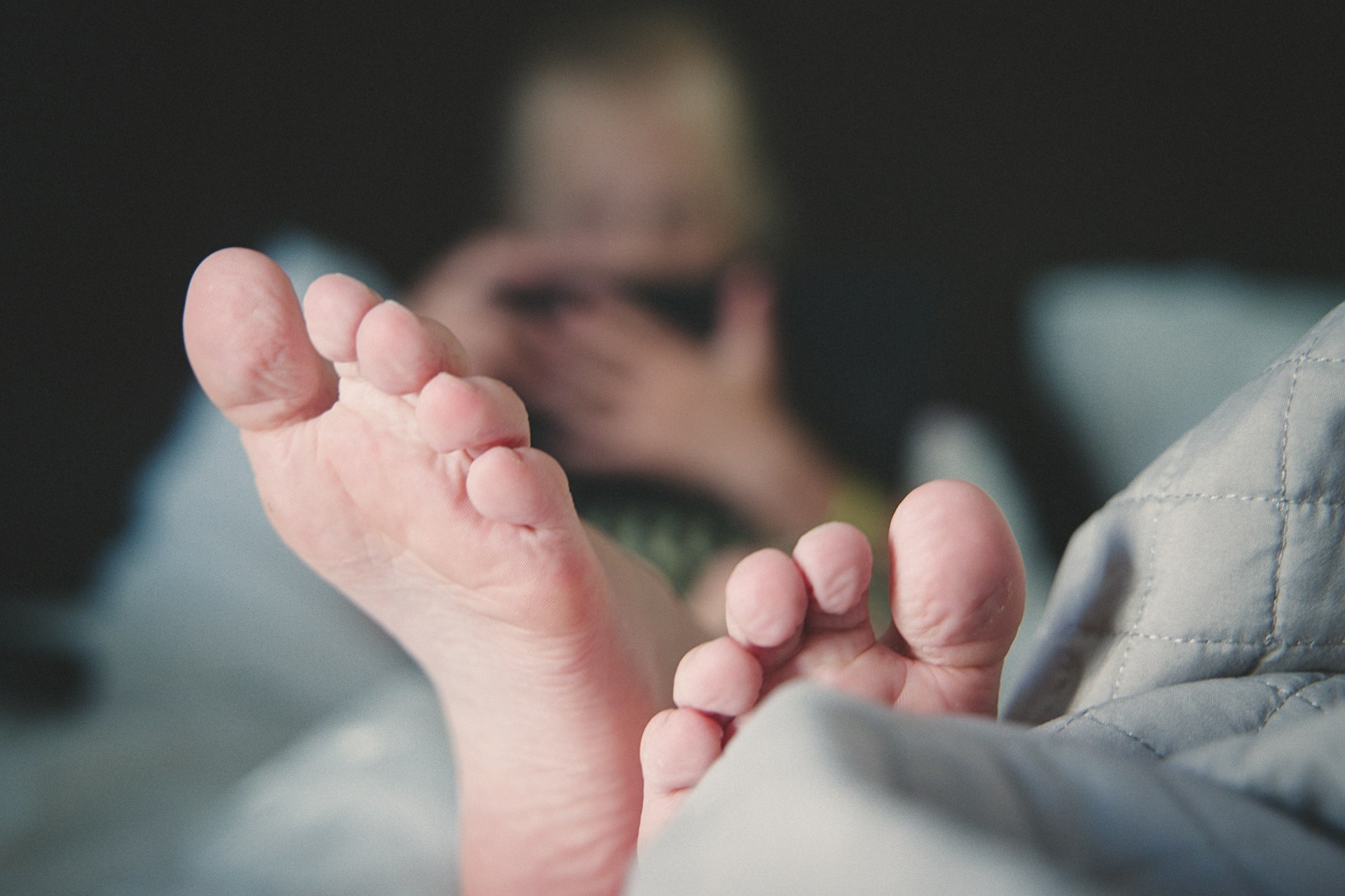 Person lying in bed with feet visible, illustrating a common position where hands or feet may temporarily fall asleep from pressure on a nerve.