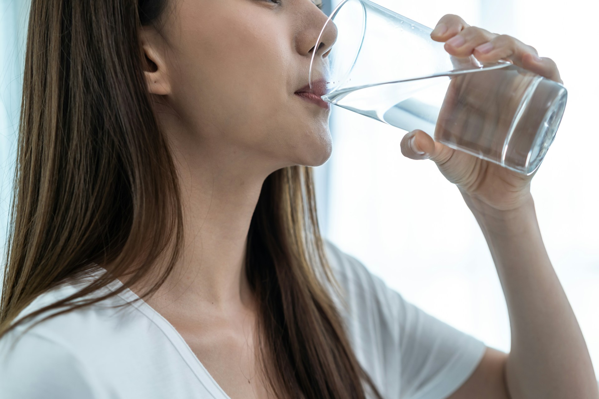 Close-up of a person drinking a glass of water.