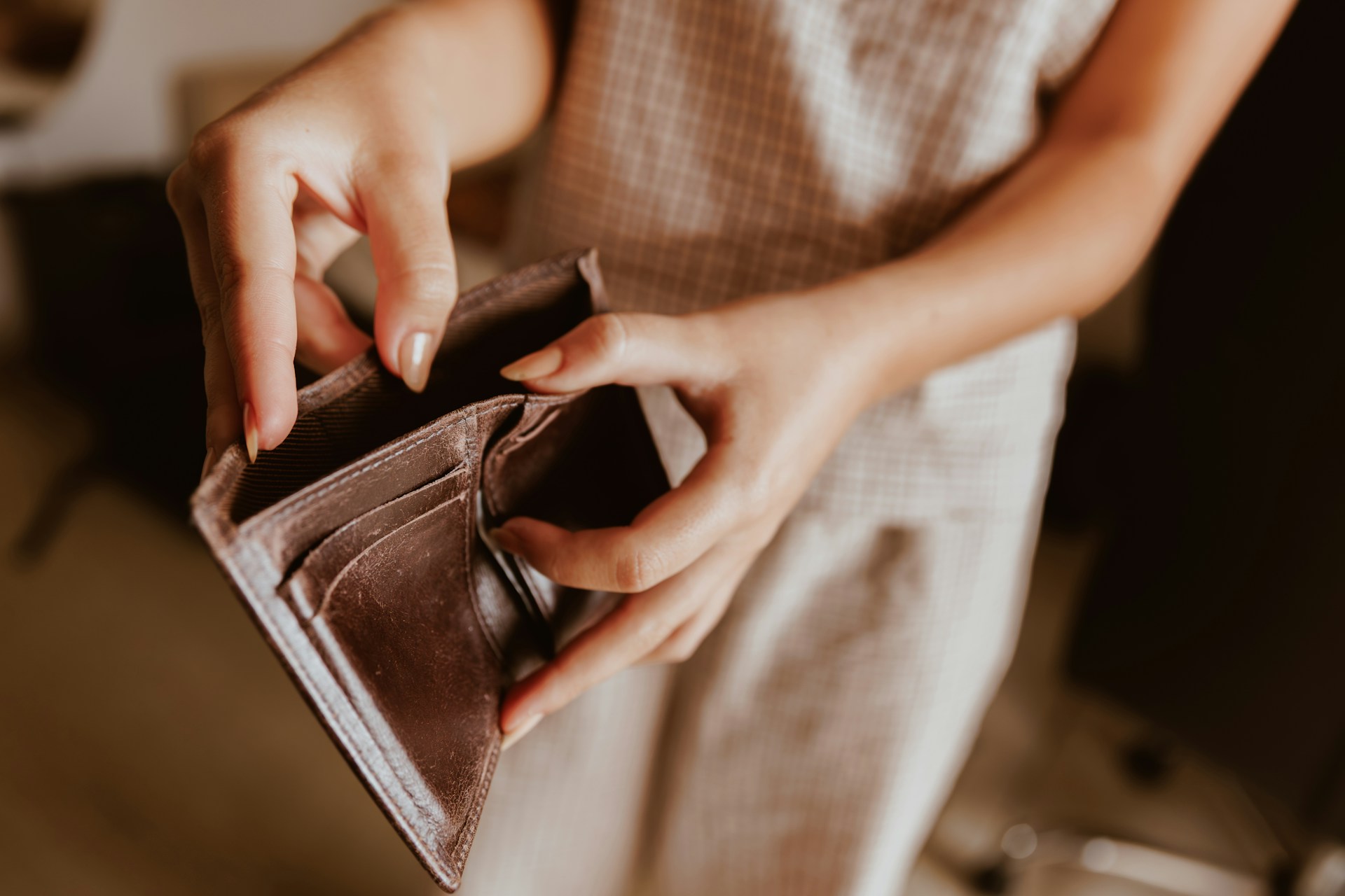erson holding an empty wallet while standing indoors, representing insufficient funds and overdraft protection.