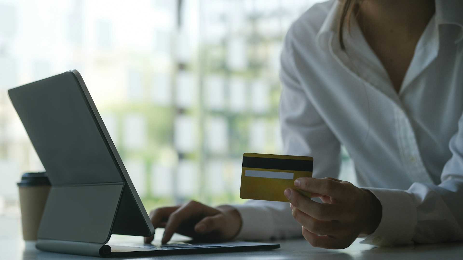 Person holding a bank card while using a tablet to view or manage an online banking transaction.