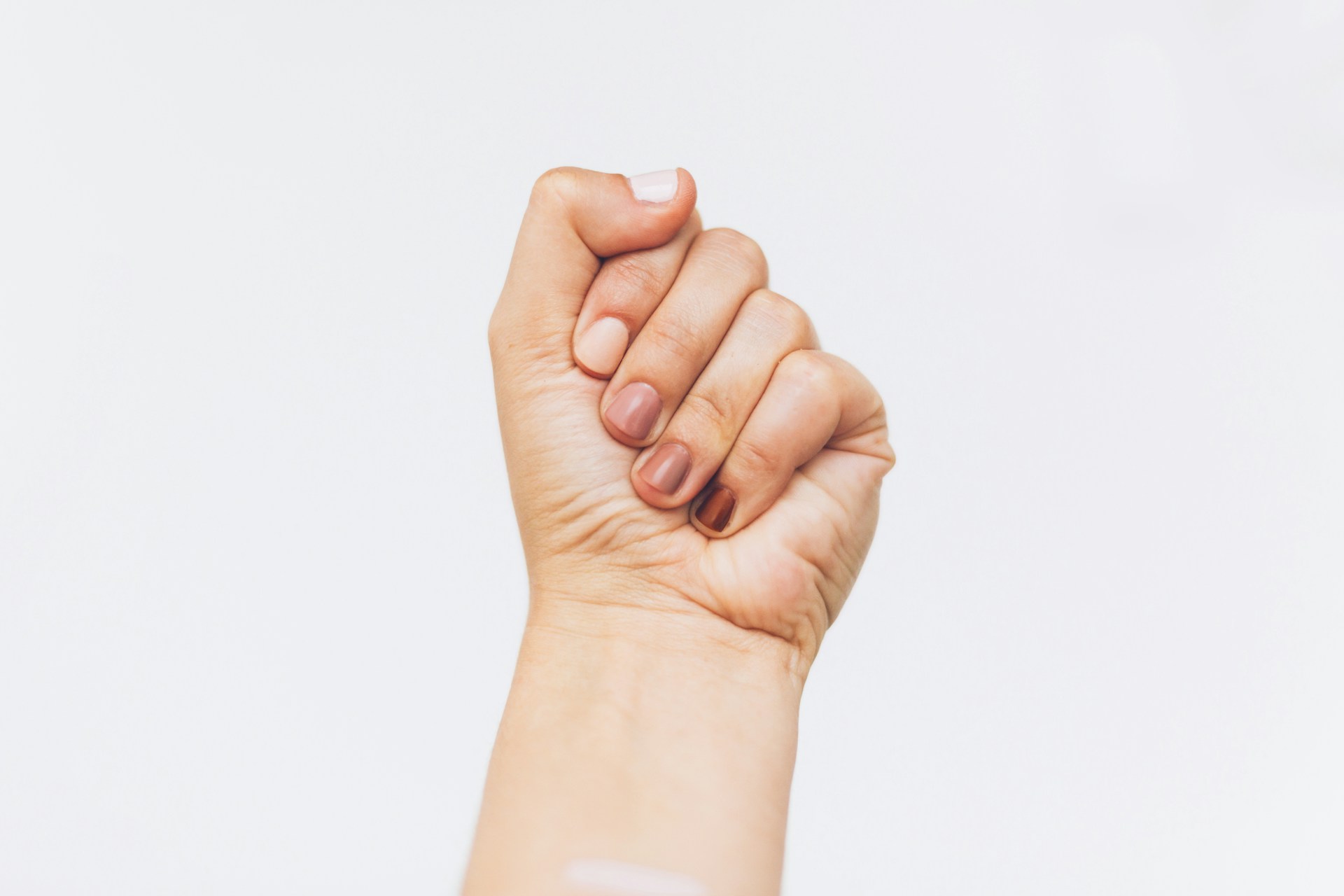 Person holding one hand raised against a white background.