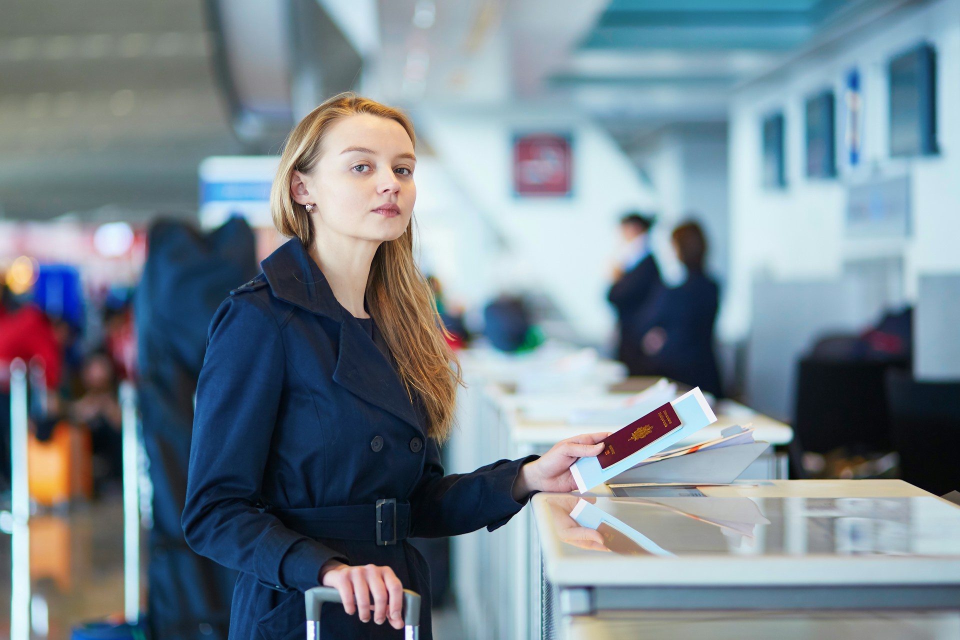 Traveler presenting a passport to an airline representative at an airport check-in counter.