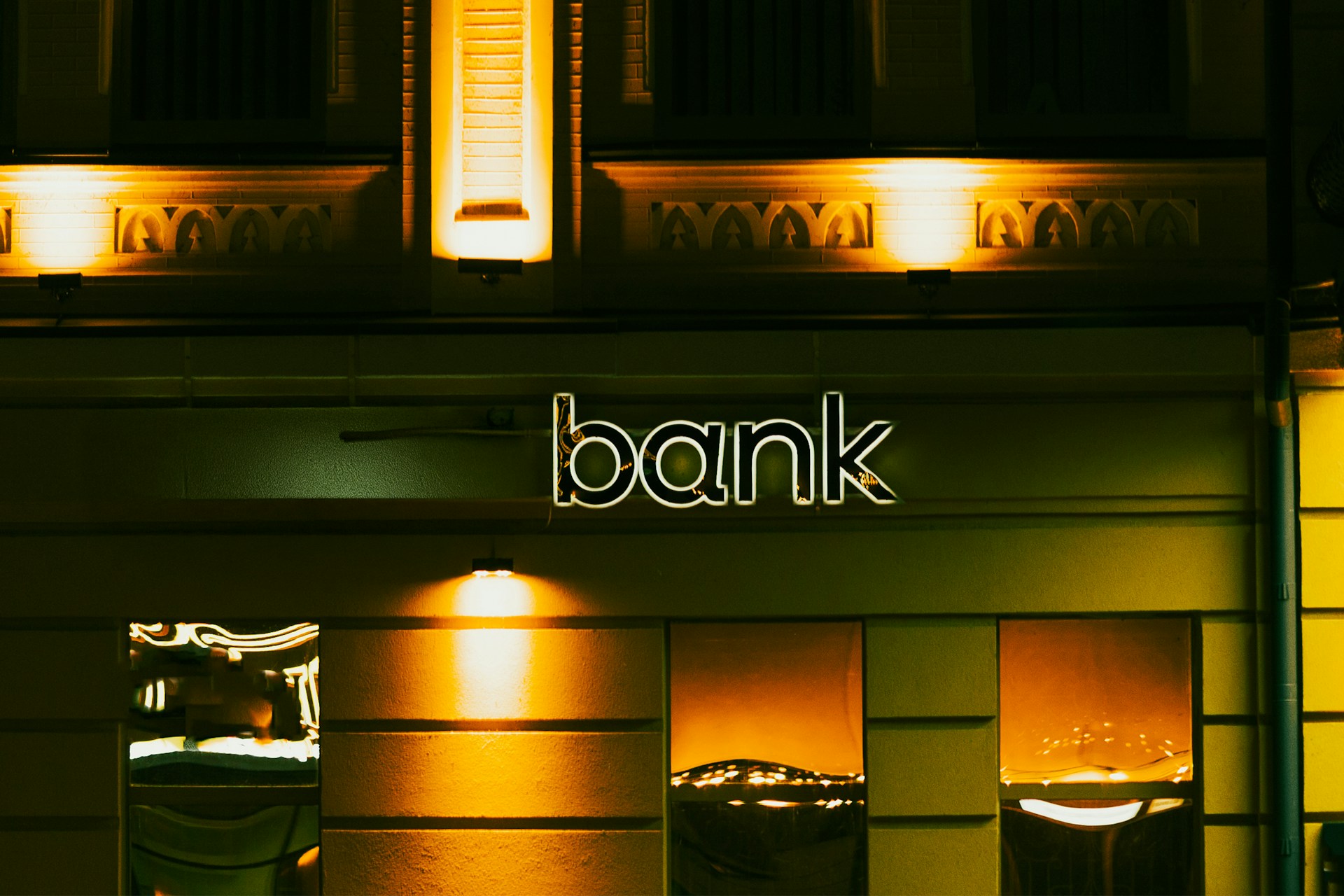 uminated bank sign on the exterior of a bank building at night.