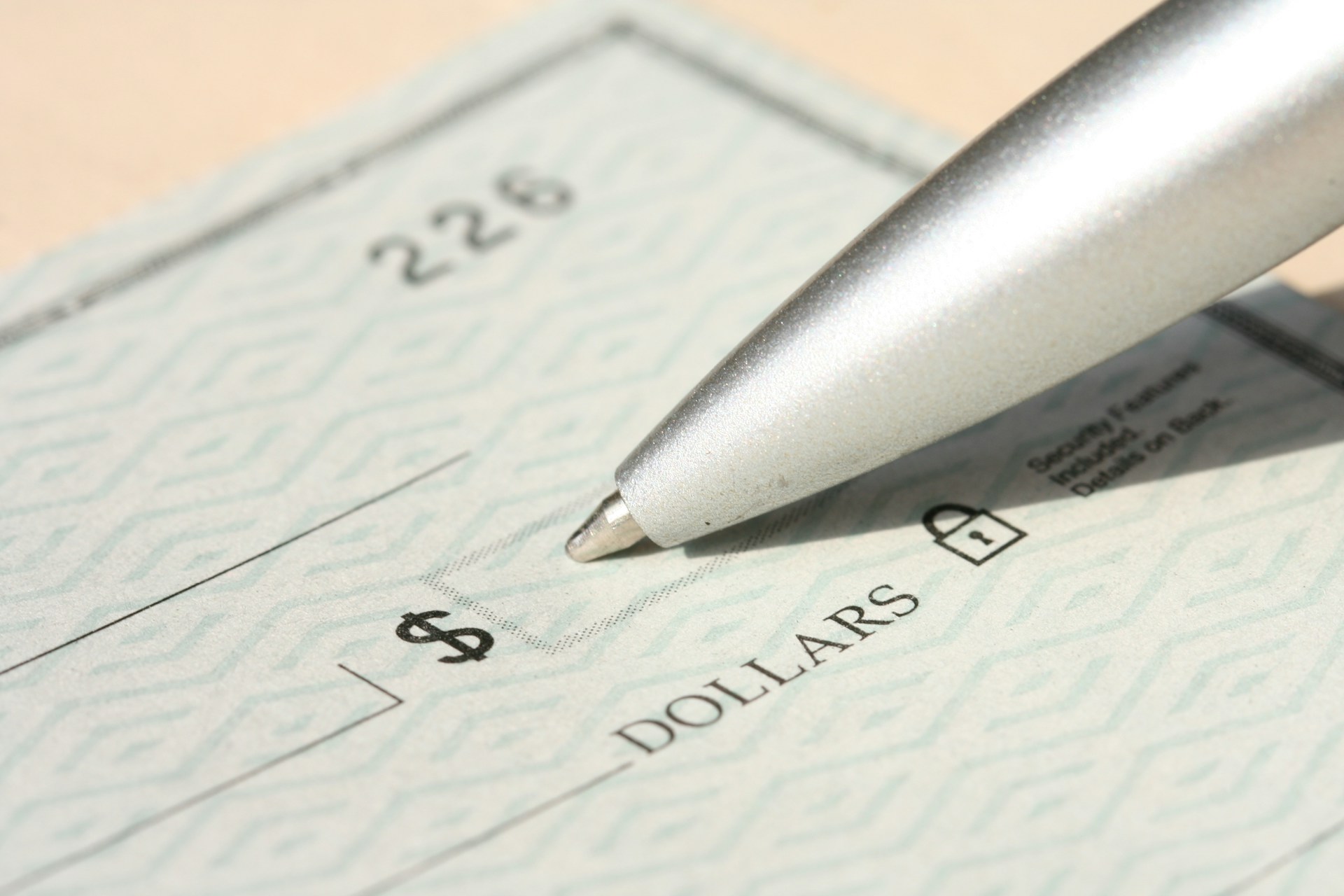 Pen resting on a paper check before it is completed