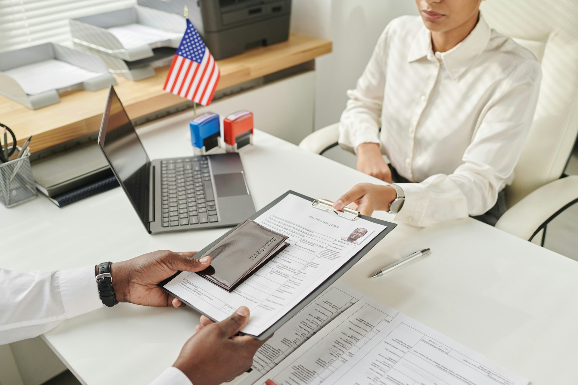 Traveler submitting visa paperwork to a staff member during the visa application process.