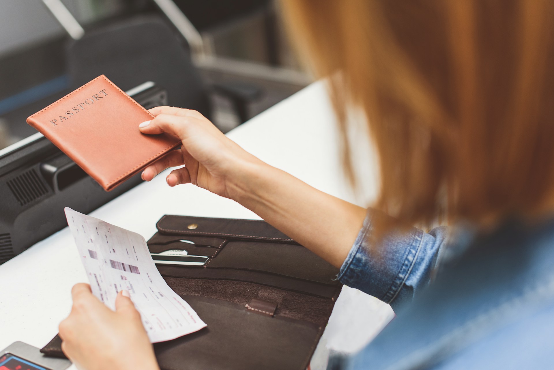 Traveler presenting a passport and boarding pass to an airline check-in agent during document verification