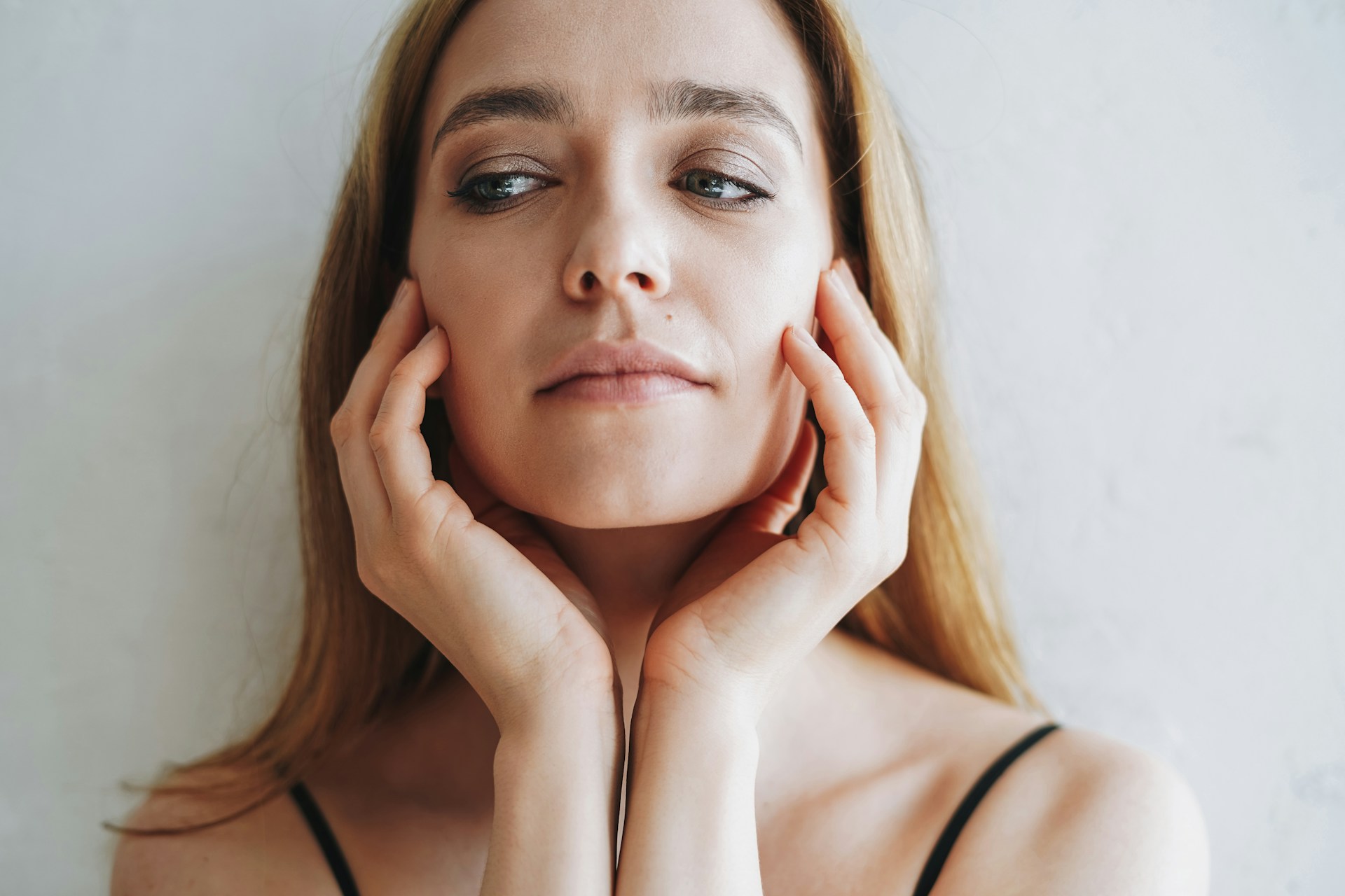 Woman touching her ear while listening, illustrating the sensation of a plugged ear.