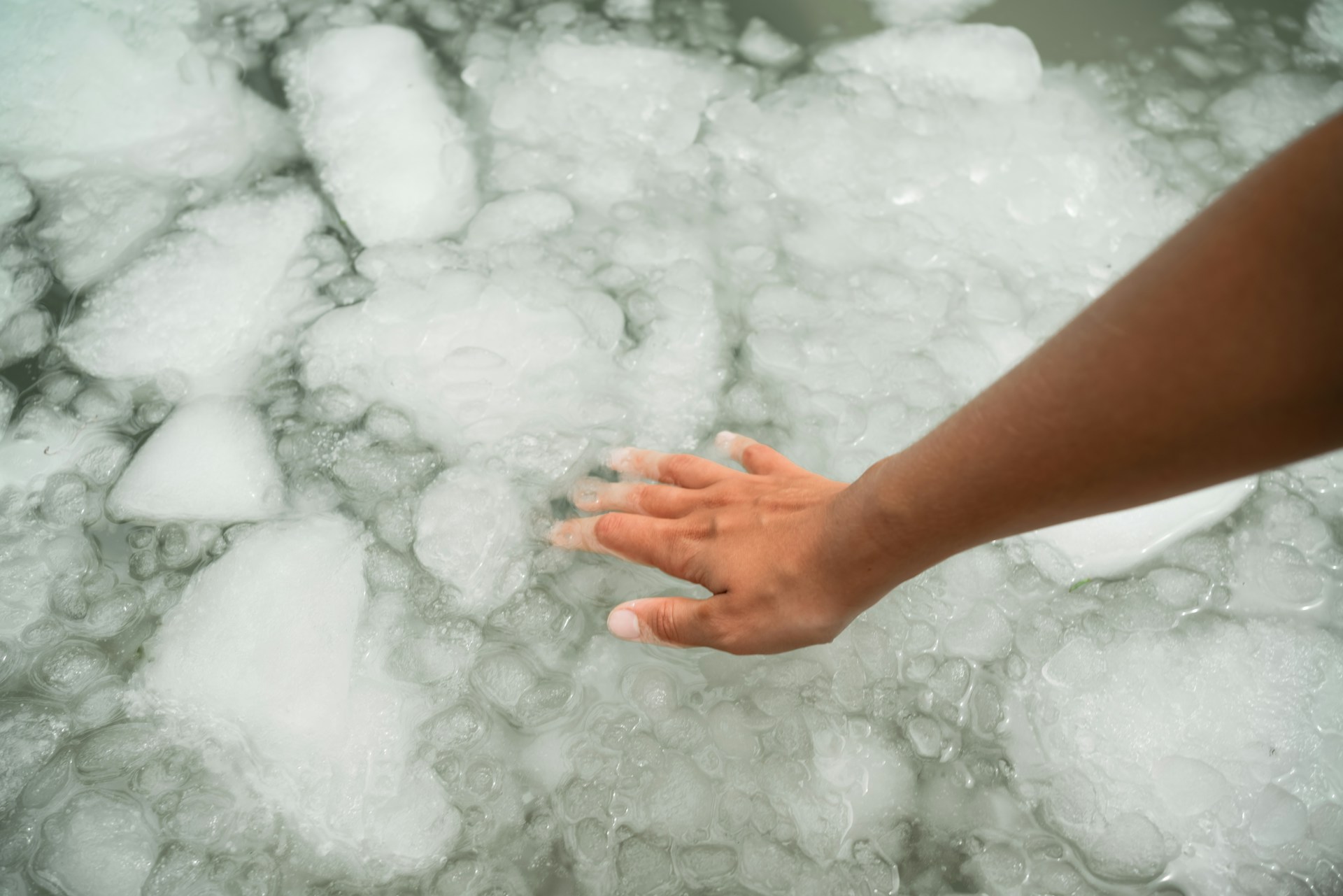 Hand reaching into ice, illustrating how cold exposure affects blood flow to the fingers.