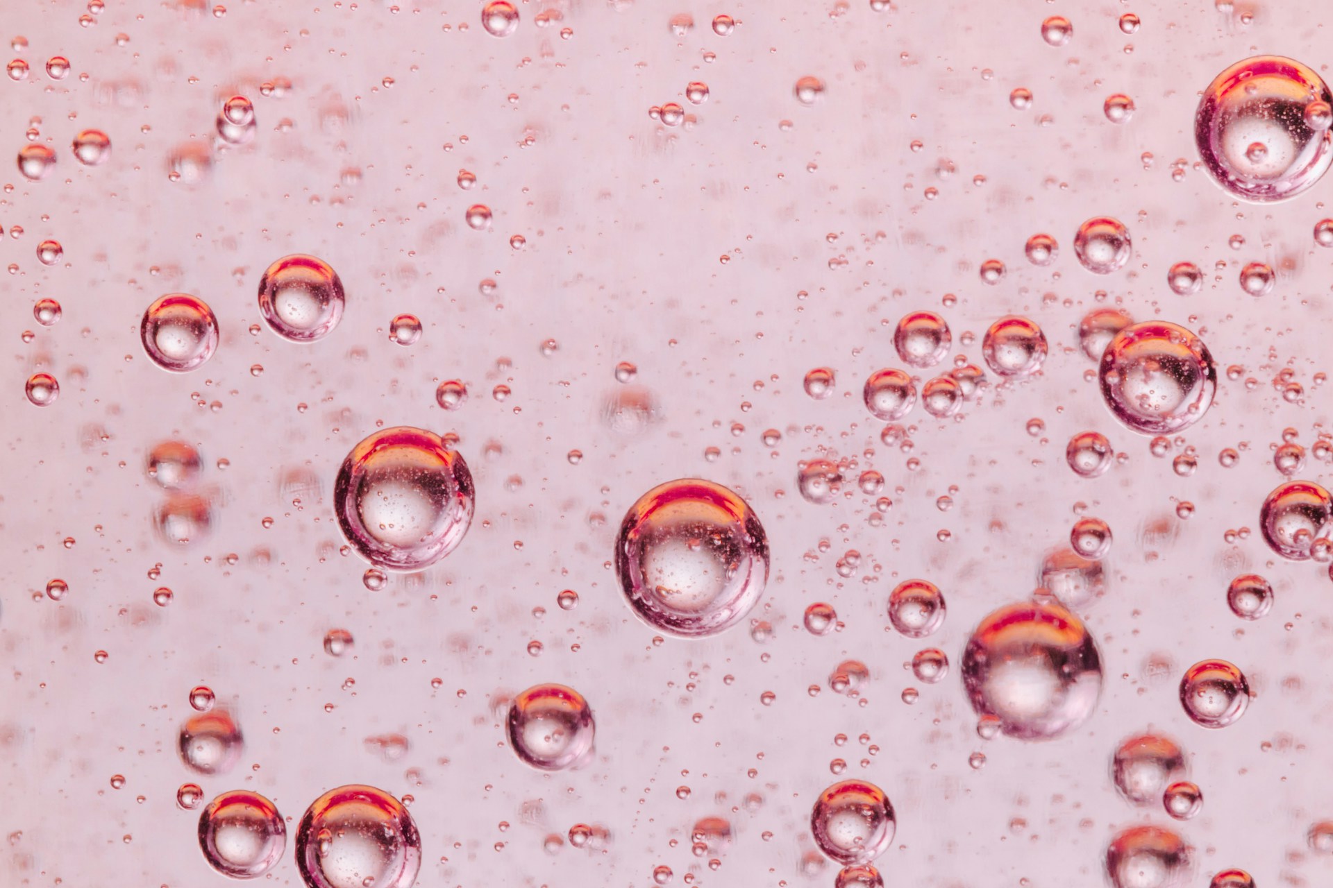 Close-up of clear water droplets suspended in the air against a soft blue background.