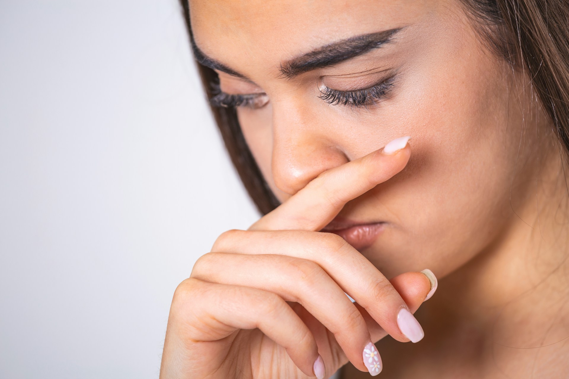Close-up of a person pinching their nose to block an unpleasant odor.