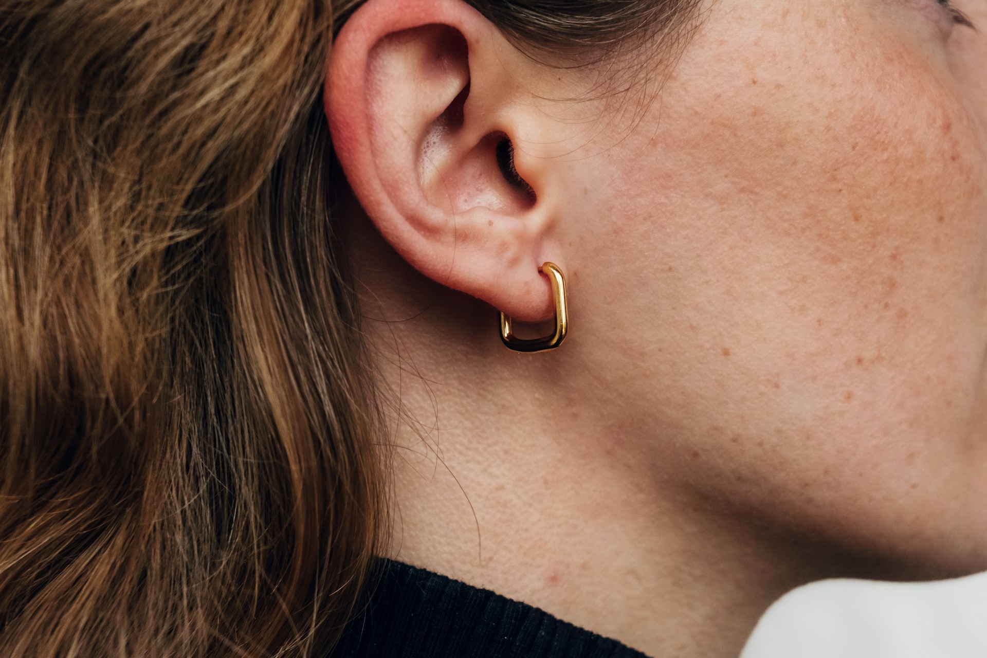 Close-up of a person's outer ear with an earring.