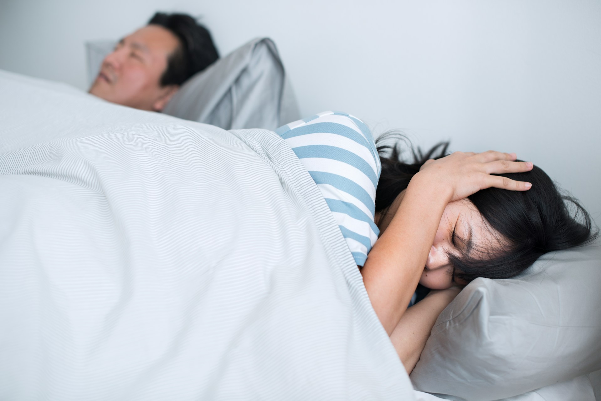 Person sleeping while another person lies awake because of loud snoring.