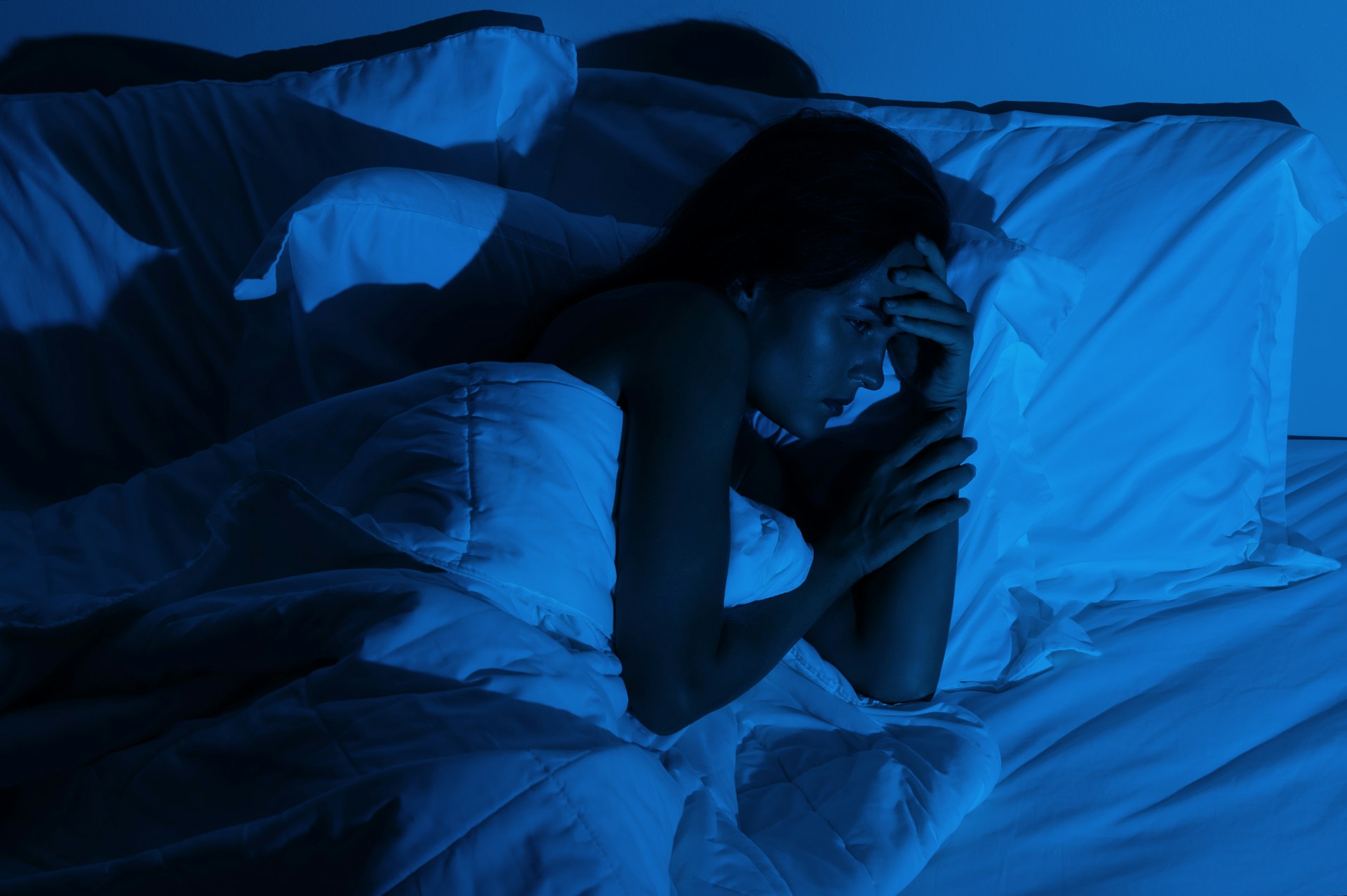 Person awake in bed during the night in a dark bedroom after suddenly waking from sleep.