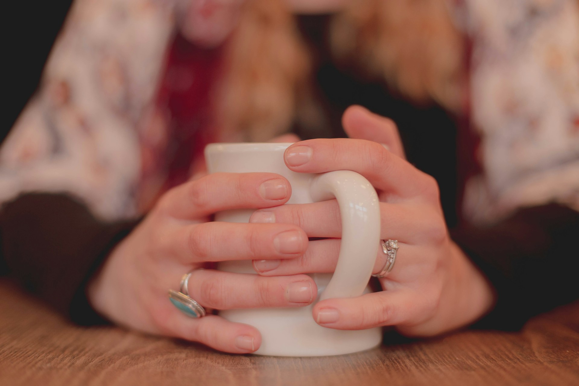 Person holding a warm mug with both hands on a cool day.
