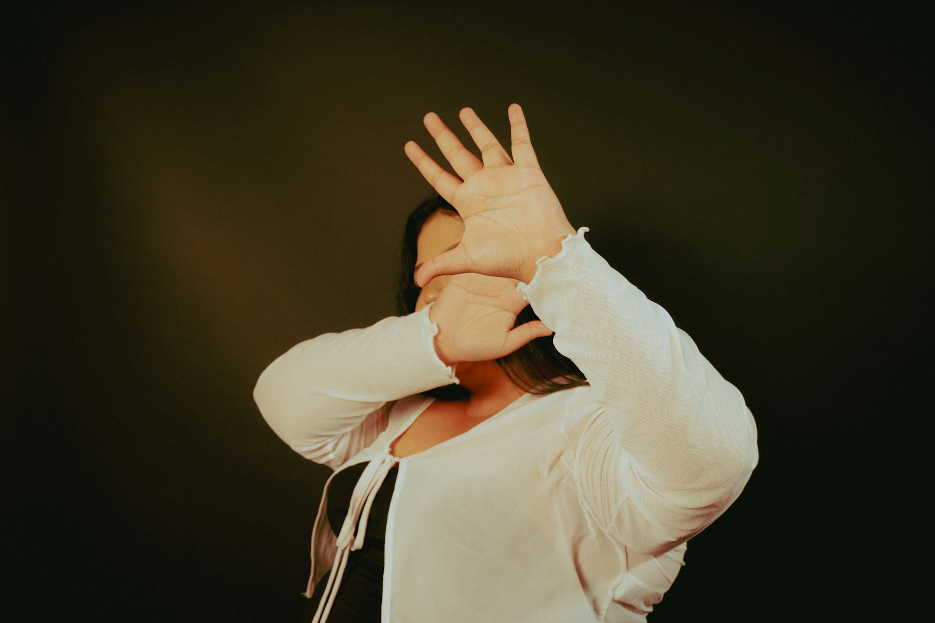 Person raising their hands in front of their face in a protective reflex.