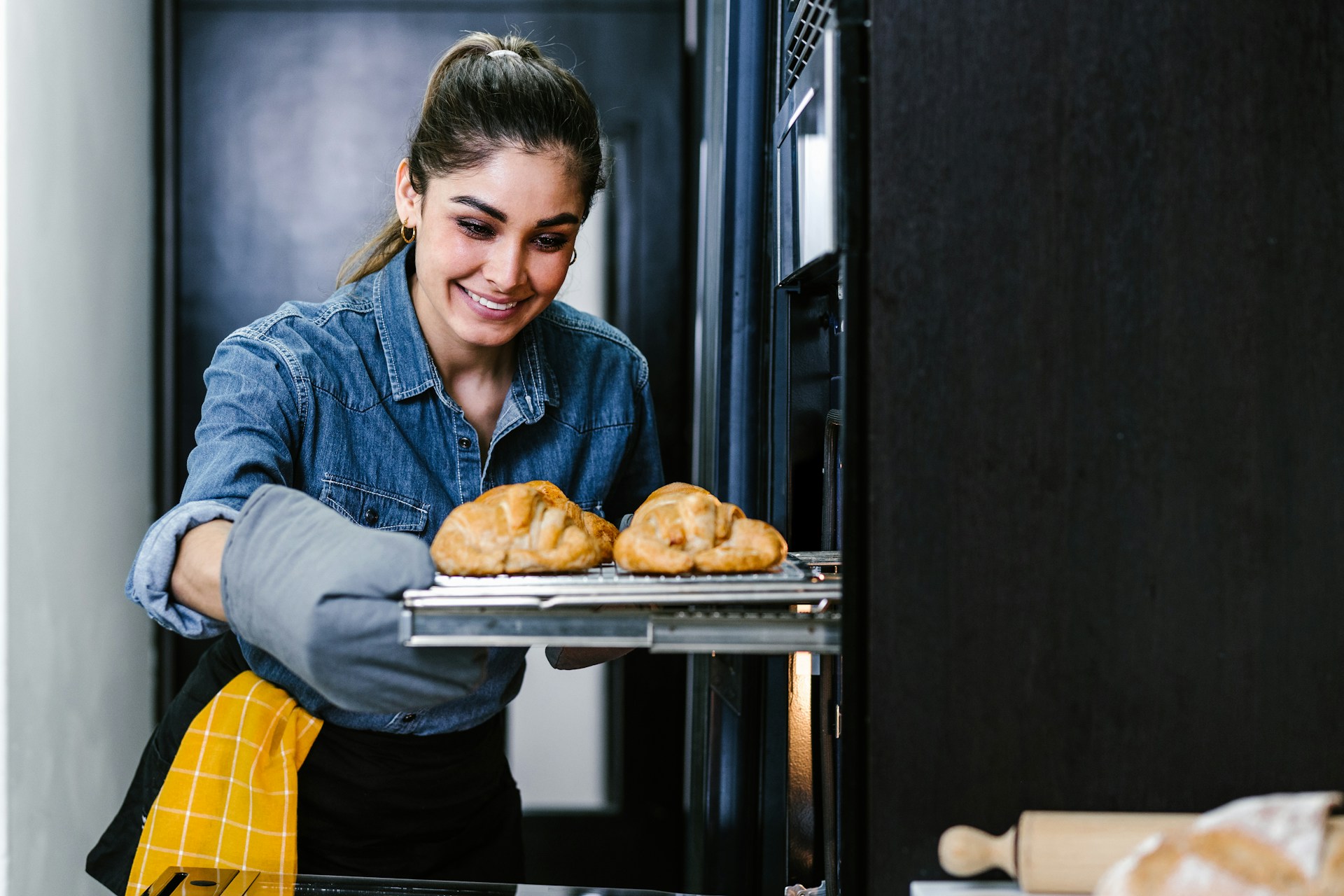 Woman checking freshly baked pastries in an oven before eating.