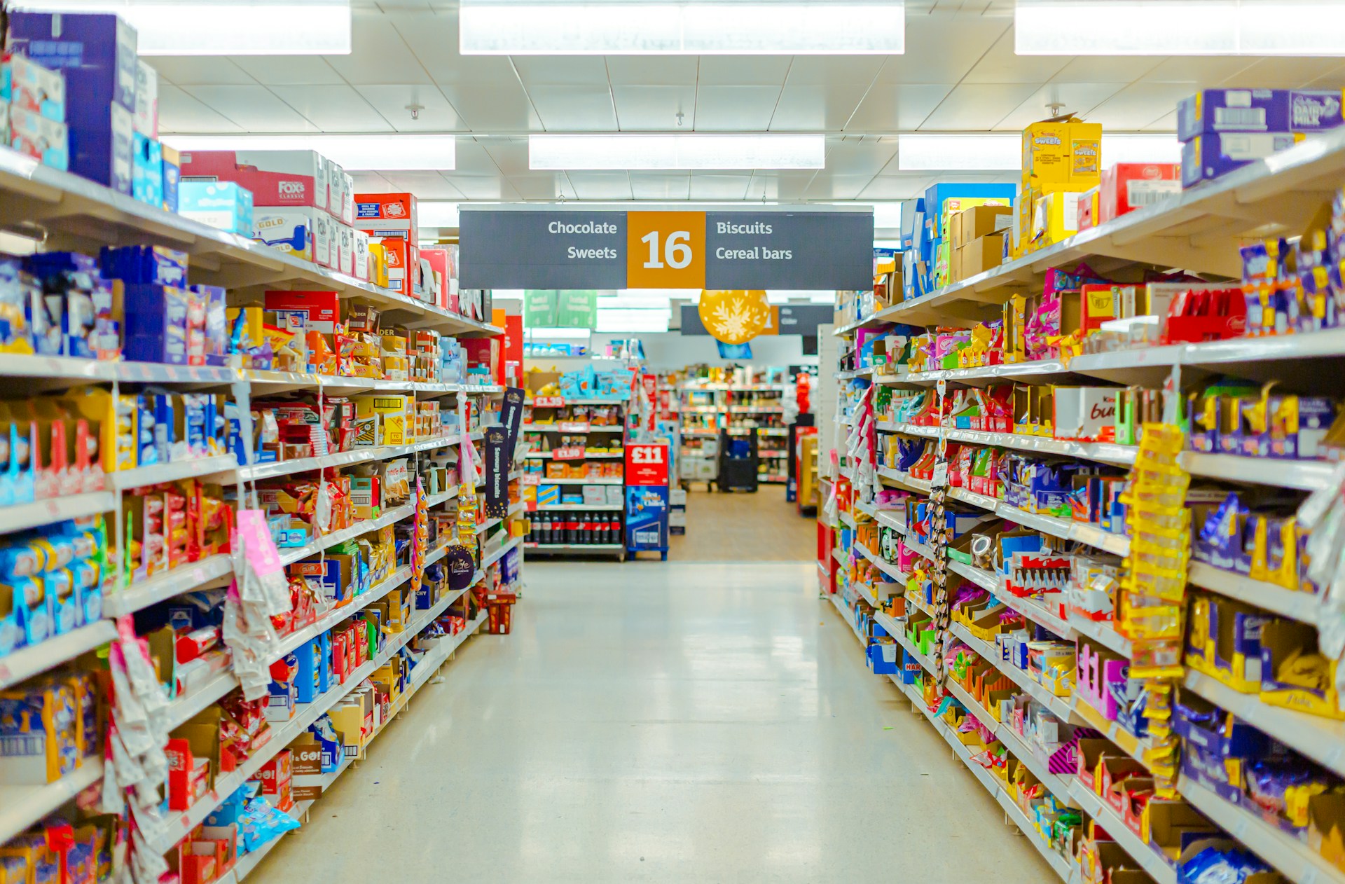 Grocery store aisle with shelves filled with packaged food and snacks.