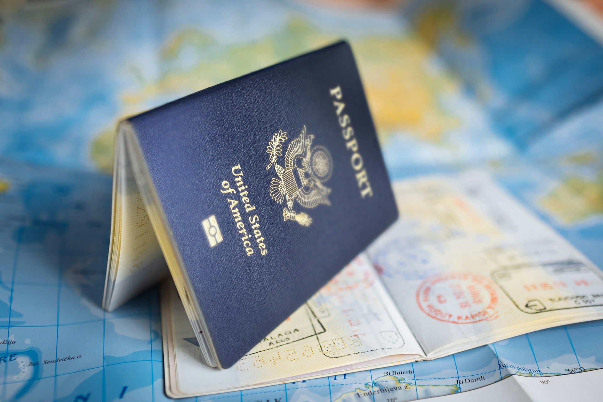 A United States passport resting on a colorful world map